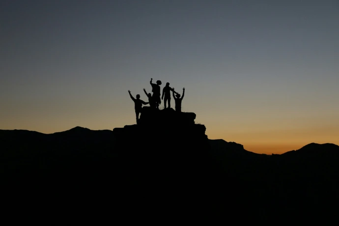 Silhouette von Menschen, die während der goldenen Stunden auf einem Hochland stehen