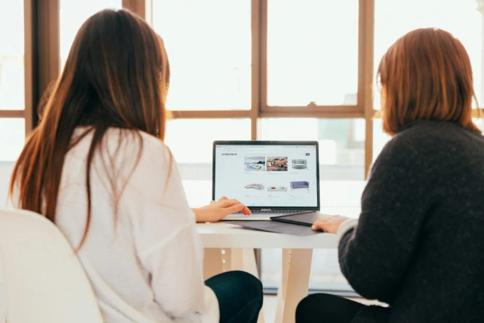 two women talking while looking at a laptop computer